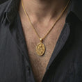 Load image into Gallery viewer, Gold plated Saint Rita pendant necklace worn on the neck, captured on a human model in a premium dark-toned lifestyle frame.
