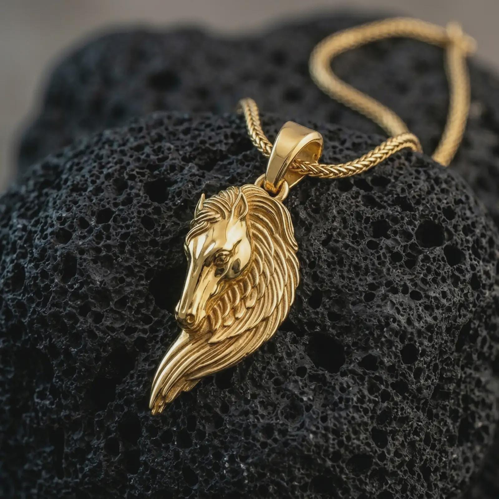 Gold plated Pegasus wing horse pendant necklace presented on porous volcanic rock, highlighting the mythological equestrian design in a luxurious close-up jewelry image.