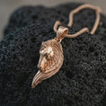Load image into Gallery viewer, Rose gold plated Pegasus wing horse pendant necklace on dark volcanic rock, photographed in a detailed premium studio macro view.
