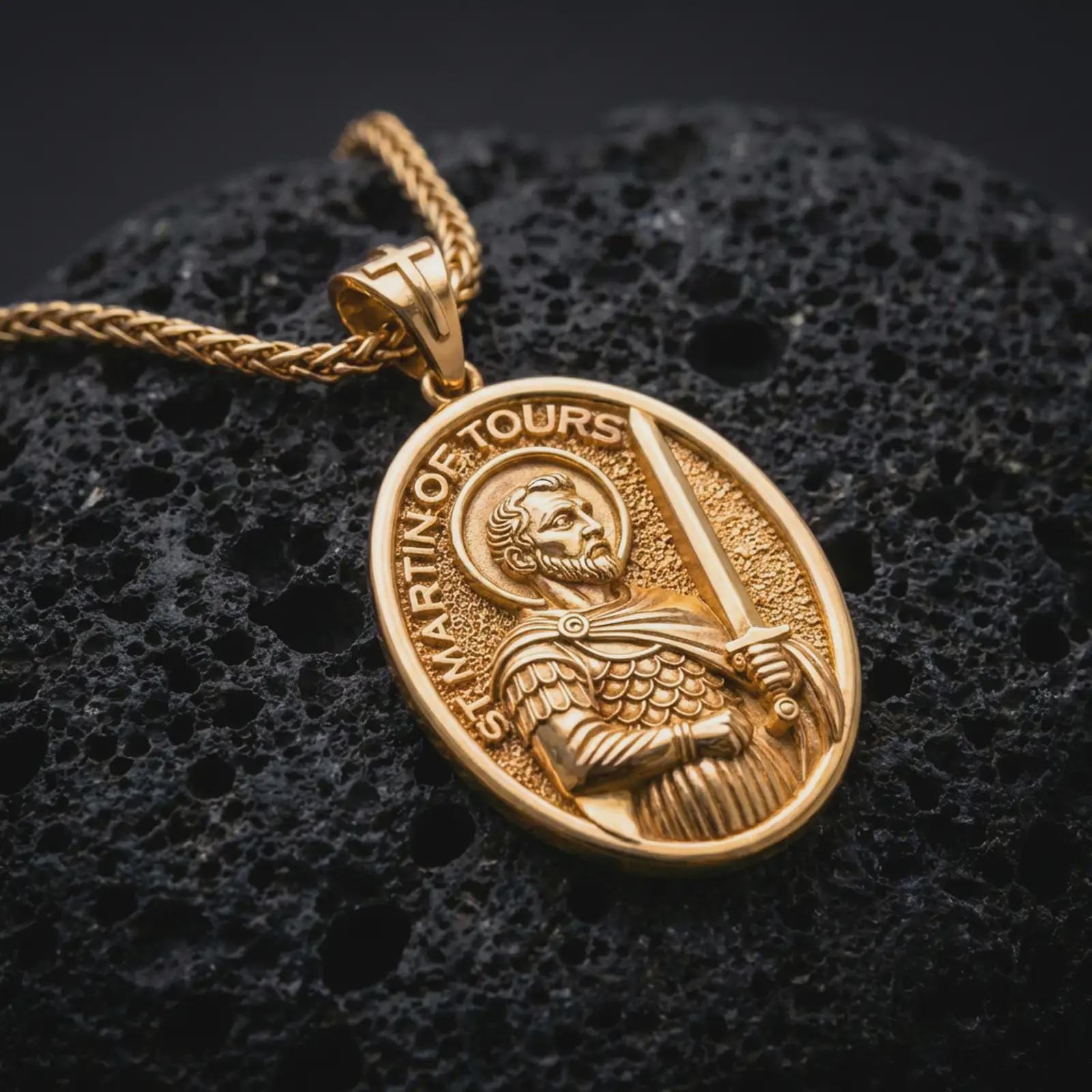 Gold plated Saint Martin of Tours pendant necklace presented on porous volcanic rock, highlighting the oval medallion form and sacred devotional design in a luxurious close-up jewelry image.