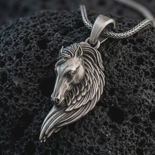 Sterling silver Pegasus wing horse pendant necklace with an oxidized finish resting on textured volcanic rock, captured in a close-up premium studio composition.