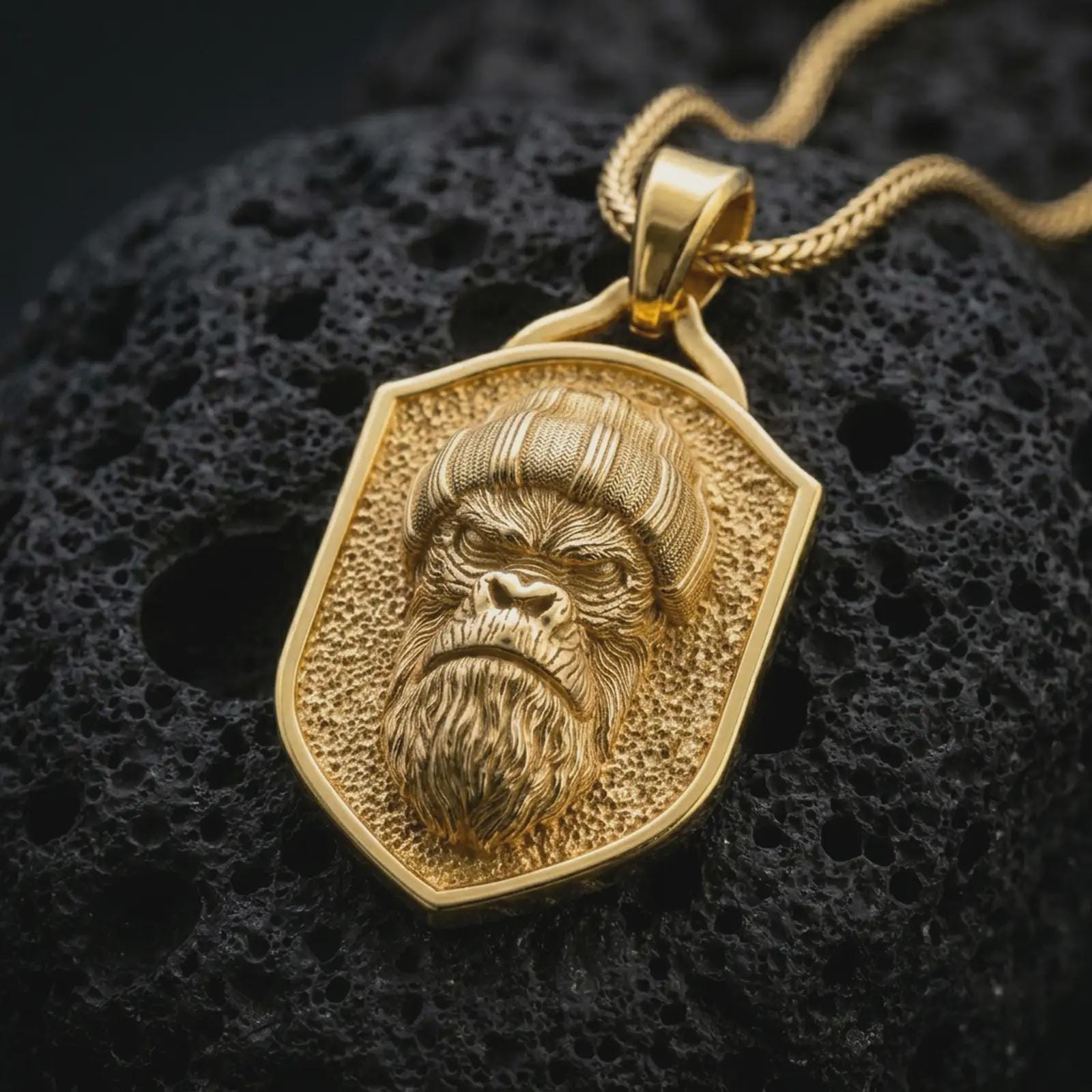 Gold plated gorilla shield pendant necklace presented on porous volcanic rock, highlighting the urban primate motif in a luxurious close-up jewelry image.