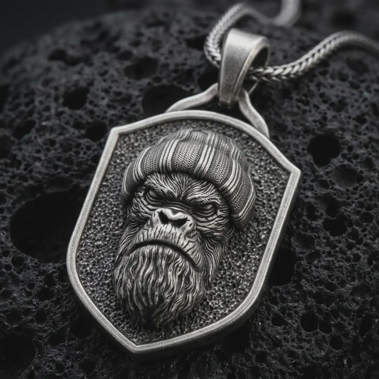 Sterling silver gorilla shield pendant necklace with an oxidized finish resting on textured volcanic rock, captured in a close-up premium studio composition.