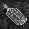 Load image into Gallery viewer, Sterling silver Jesus INRI crucifixion pendant necklace with an oxidized finish resting on textured volcanic rock, captured in a close-up premium studio composition.

