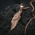 Load image into Gallery viewer, Rose gold plated raven pendant necklace on dark volcanic rock, photographed in a detailed premium studio macro view.
