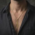 Load image into Gallery viewer, Gold plated Dragonslayer sword pendant necklace worn on the neck, captured on a human model in a premium dark-toned lifestyle frame.
