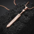 Load image into Gallery viewer, Rose gold plated Dragonslayer sword pendant necklace on dark volcanic rock, photographed in a detailed premium studio macro view.
