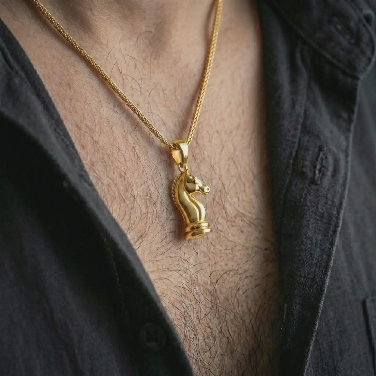 Gold plated knight chess piece pendant necklace worn on the neck, captured on a human model in a premium dark-toned lifestyle frame.