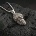 Load image into Gallery viewer, Polished silver gorilla head pendant necklace displayed on black volcanic rock, shown in a refined macro product shot with knit beanie detail, sculpted beard texture, and urban primate character.
