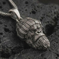 Load image into Gallery viewer, Sterling silver gorilla head pendant necklace with an oxidized finish resting on textured volcanic rock, captured in a close-up premium studio composition.
