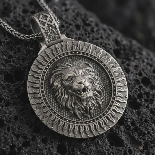 Sterling silver Viking lion medallion pendant necklace with an oxidized finish resting on textured volcanic rock, captured in a close-up premium studio composition.