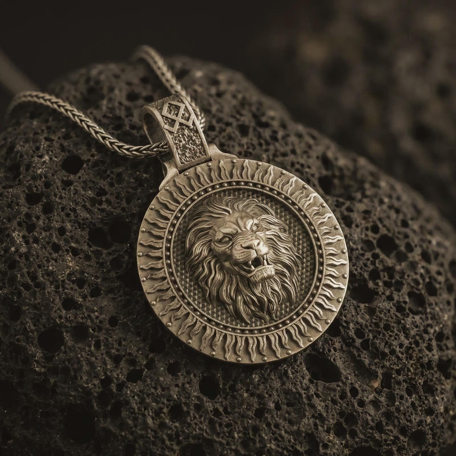 Bronze Viking lion medallion pendant necklace with an oxidized finish resting on textured volcanic rock, captured in a close-up premium studio composition.