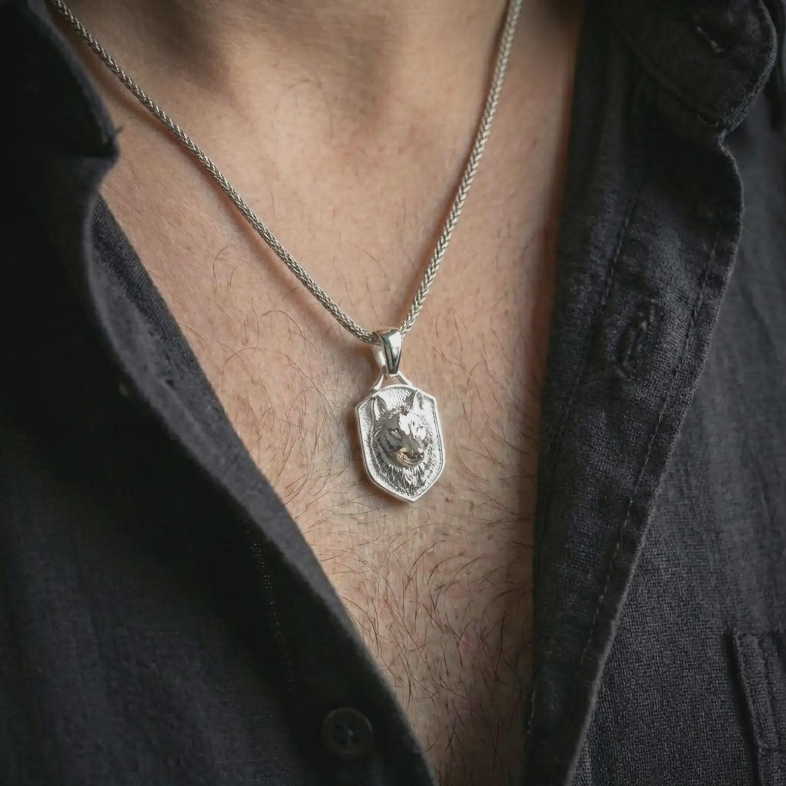 Wolf shield pendant necklace in polished silver worn on the neck, presented in a clean close-up model image with a bold wilderness-inspired look.
