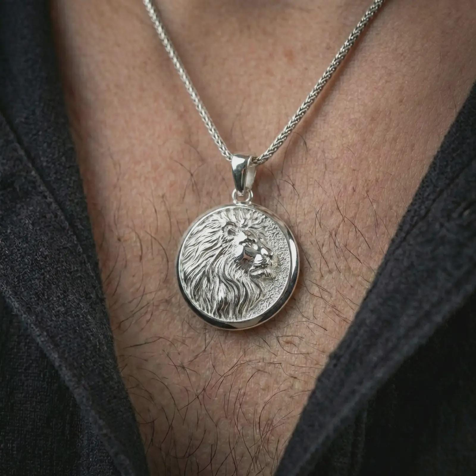 Polished silver lion medallion pendant necklace worn on the neck, presented in a clean close-up model image with an elegant and commanding masculine look.
