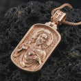 Load image into Gallery viewer, Rose gold plated Sacred Heart pendant necklace on dark volcanic rock, photographed in a detailed premium studio macro view.
