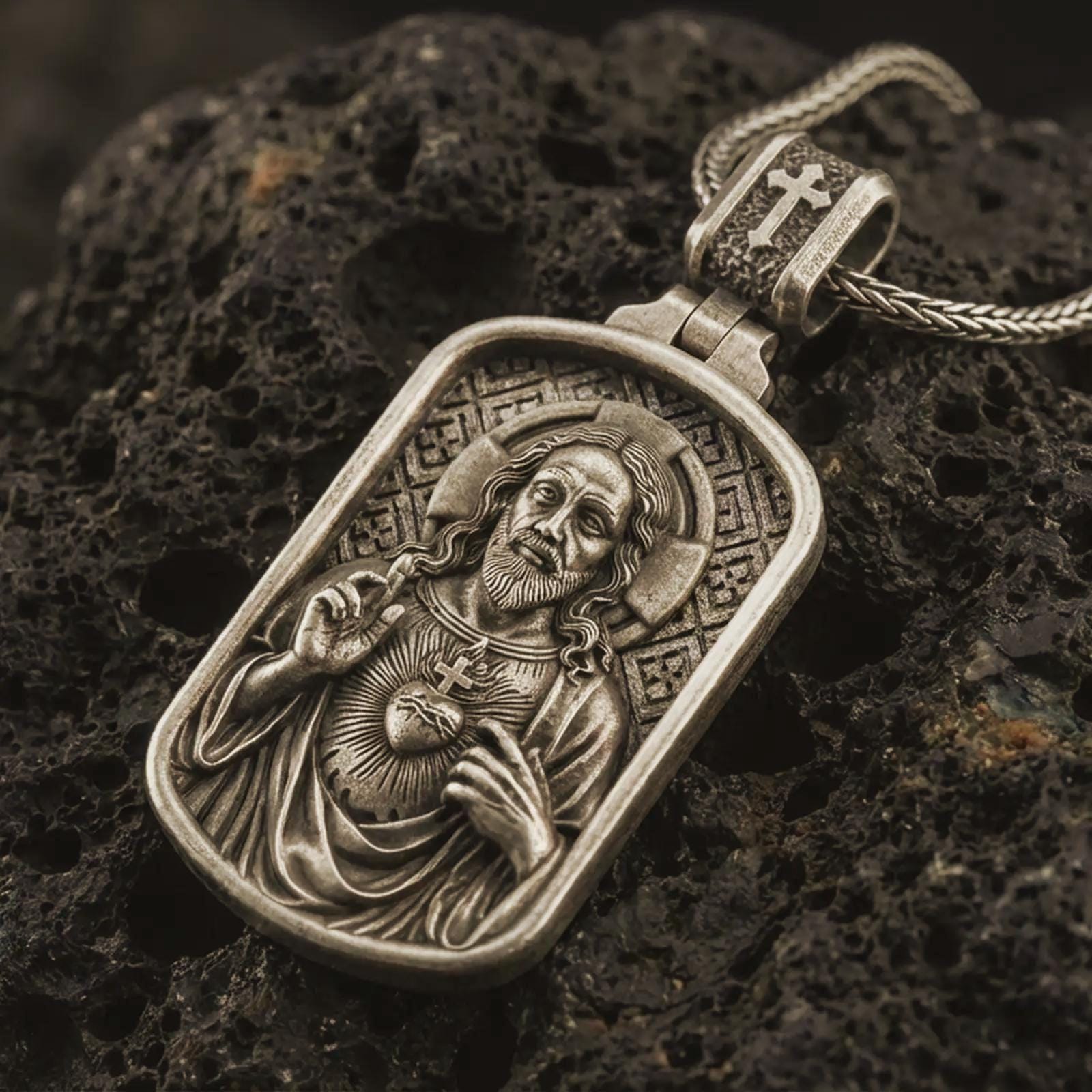 Bronze Sacred Heart pendant necklace with an oxidized finish resting on textured volcanic rock, captured in a close-up premium studio composition.