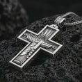 Load image into Gallery viewer, Polished silver Cristo Protetor cross pendant necklace displayed on black volcanic rock, shown in a refined macro product shot with detailed sacred figure and radiant cross relief.
