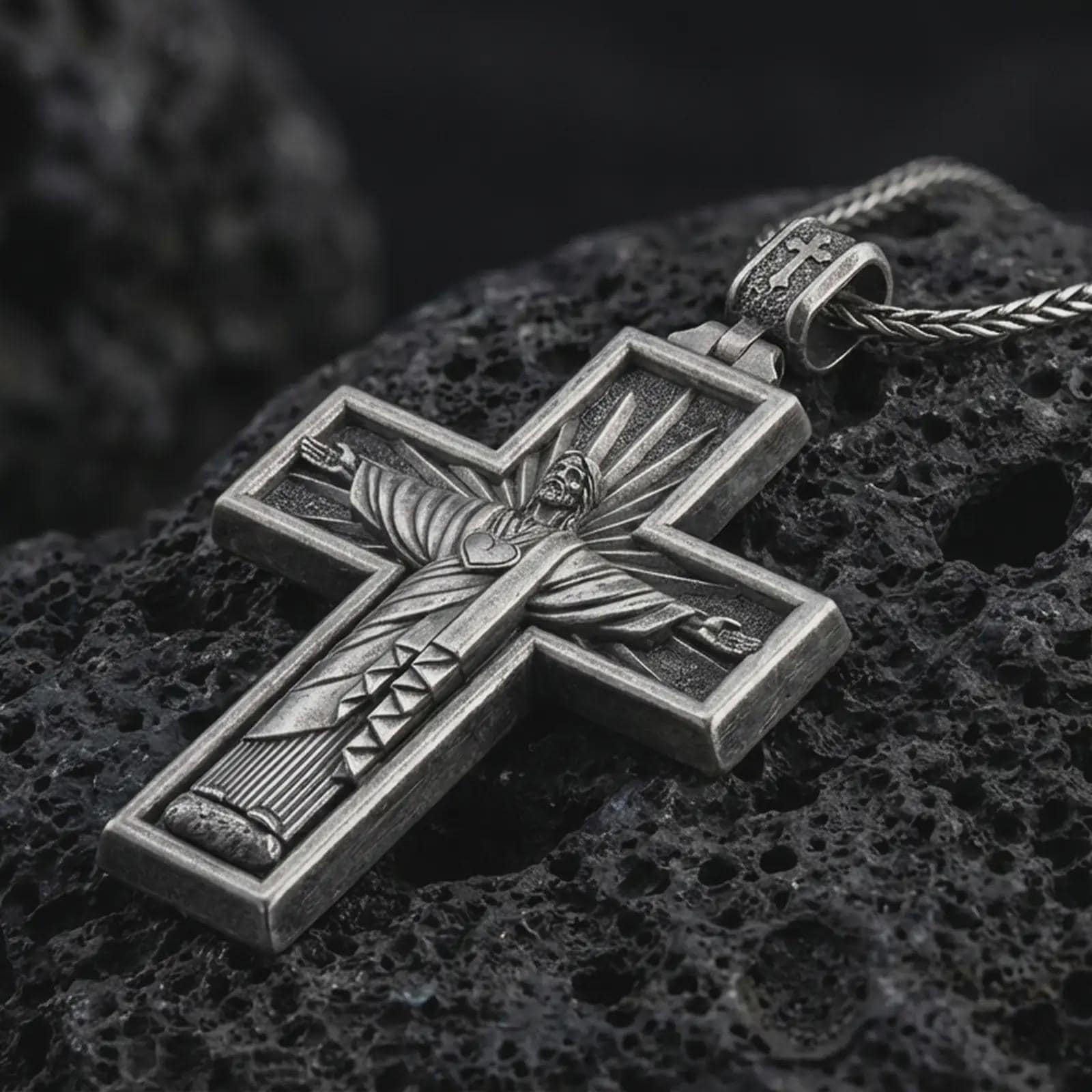 Sterling silver Cristo Protetor cross pendant necklace with an oxidized finish resting on textured volcanic rock, captured in a close-up premium studio composition.