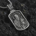 Load image into Gallery viewer, Sterling silver Saint Paul dog tag pendant necklace with an oxidized finish resting on textured volcanic rock, captured in a close-up premium studio composition.
