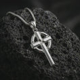 Load image into Gallery viewer, Polished silver Celtic cross pendant necklace resting on textured volcanic rock, shown in a premium macro product shot emphasizing its clean Christian silhouette and solid geometric design.

