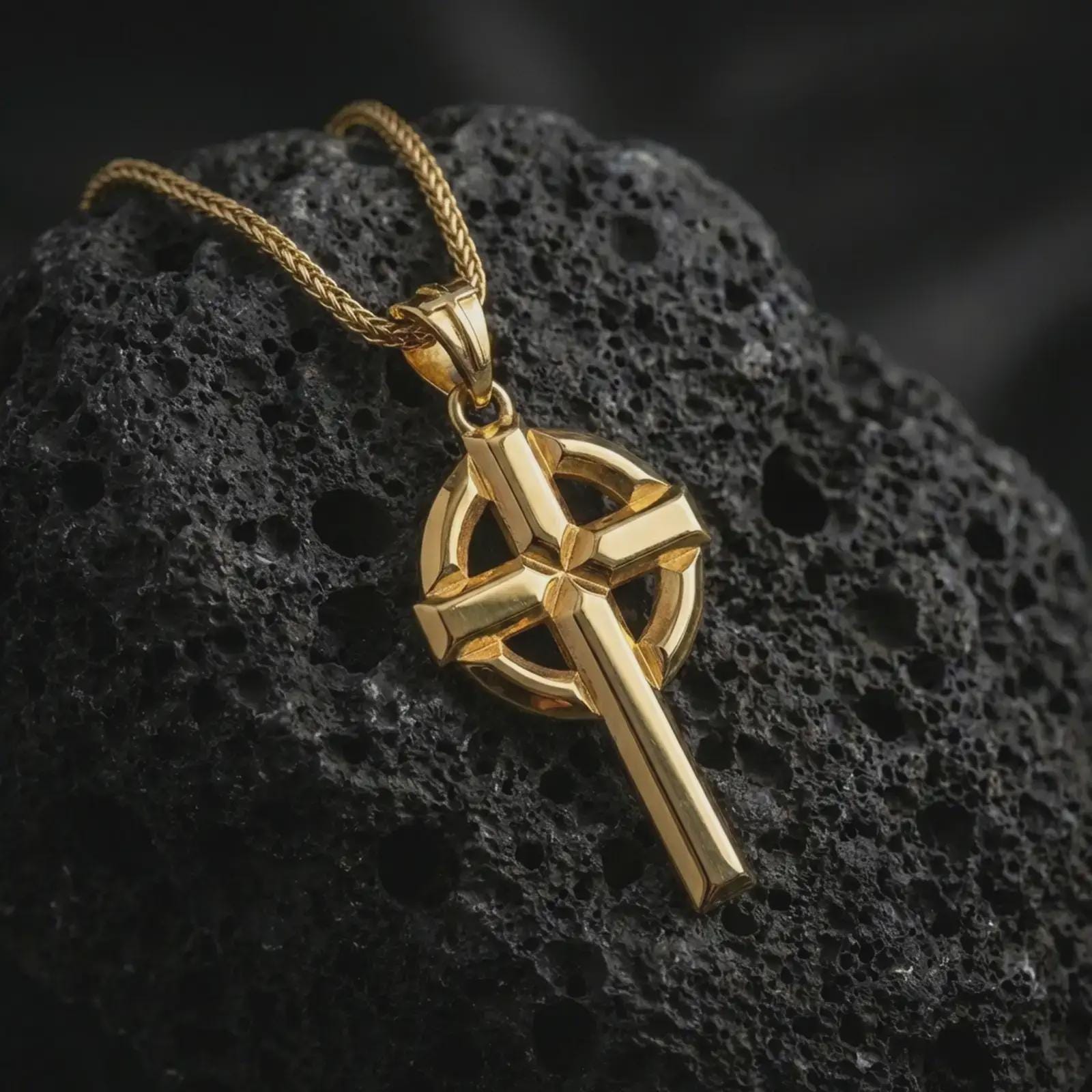 Gold plated Celtic cross pendant necklace presented on dark volcanic stone, photographed in a refined close-up composition that showcases the iconic Irish cross structure and strong metal texture.