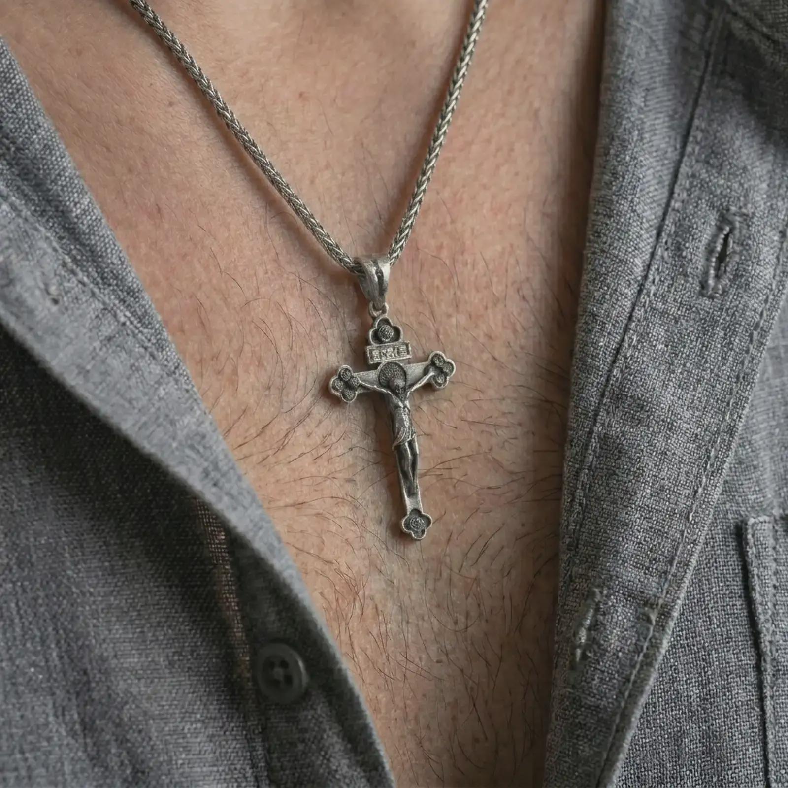 Oxidized crucifix pendant necklace worn on the neck, styled in a dark lifestyle image that highlights the devotional Christian symbol against the chest.