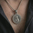 Load image into Gallery viewer, Oxidized Saint Xenia pendant necklace worn on the neck, styled in a dark lifestyle image that emphasizes the Orthodox saint medal as a meaningful devotional piece.
