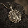 Load image into Gallery viewer, Bronze Saint Xenia pendant necklace displayed on black volcanic stone, featuring a round Orthodox medal with Saint Ksenia of Petersburg and Cyrillic inscription in a detailed macro product shot.
