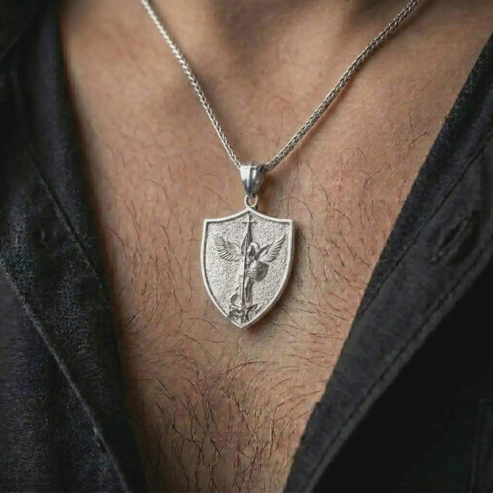 Polished silver Saint Michael pendant necklace worn on the neck, shown in a clean model shot with the shield-shaped religious pendant centered for a timeless devotional look.