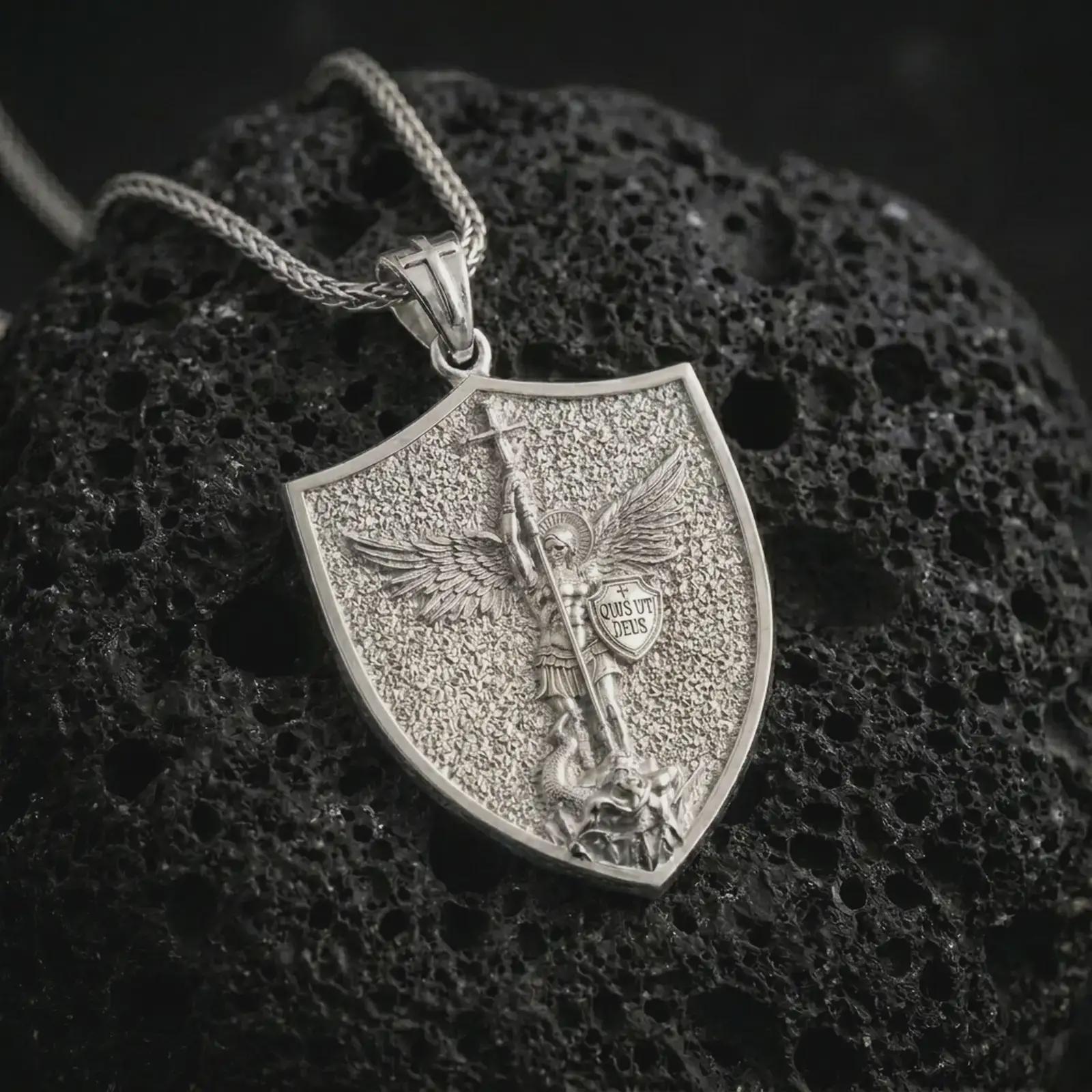 Polished silver Saint Michael pendant necklace resting on dark volcanic rock, captured in a premium close-up that highlights the angel wings, spear, and protective shield motif.