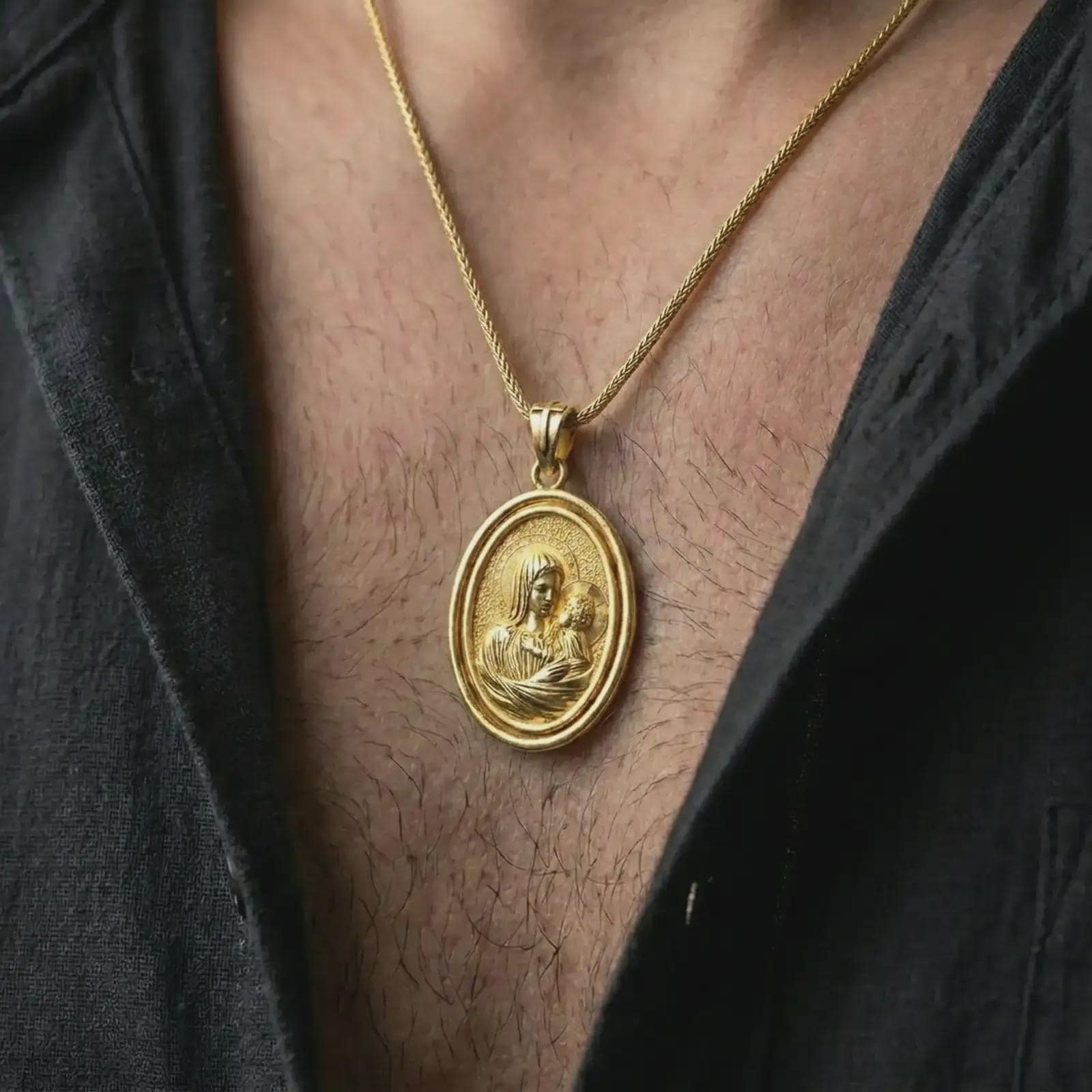 Gold plated Madonna and Child pendant necklace worn on the neck, captured in an elegant lifestyle composition that highlights the sacred mother and child image as a spiritual Christian statement piece.