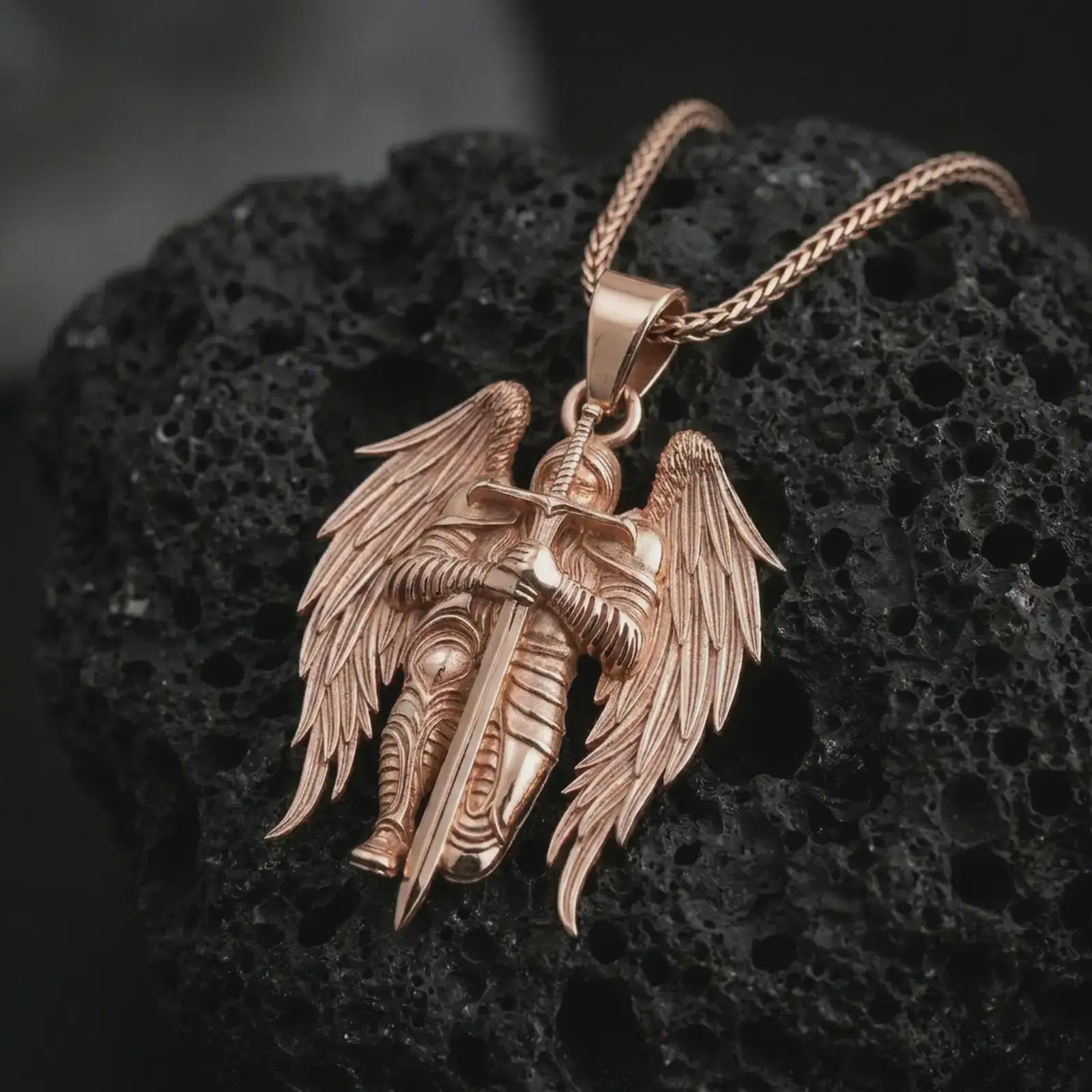 Rose gold plated angel warrior pendant necklace presented on porous volcanic stone, emphasizing the dramatic feathered wings, armor details, and elongated sword in a luxury macro shot.