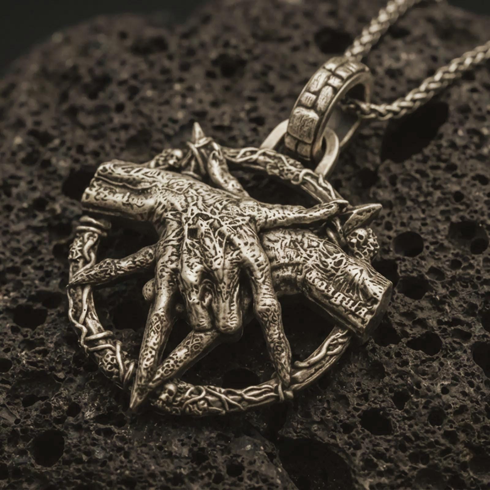 Bronze bad dream catcher pendant necklace with an oxidized finish resting on textured volcanic rock, captured in a close-up premium studio composition.