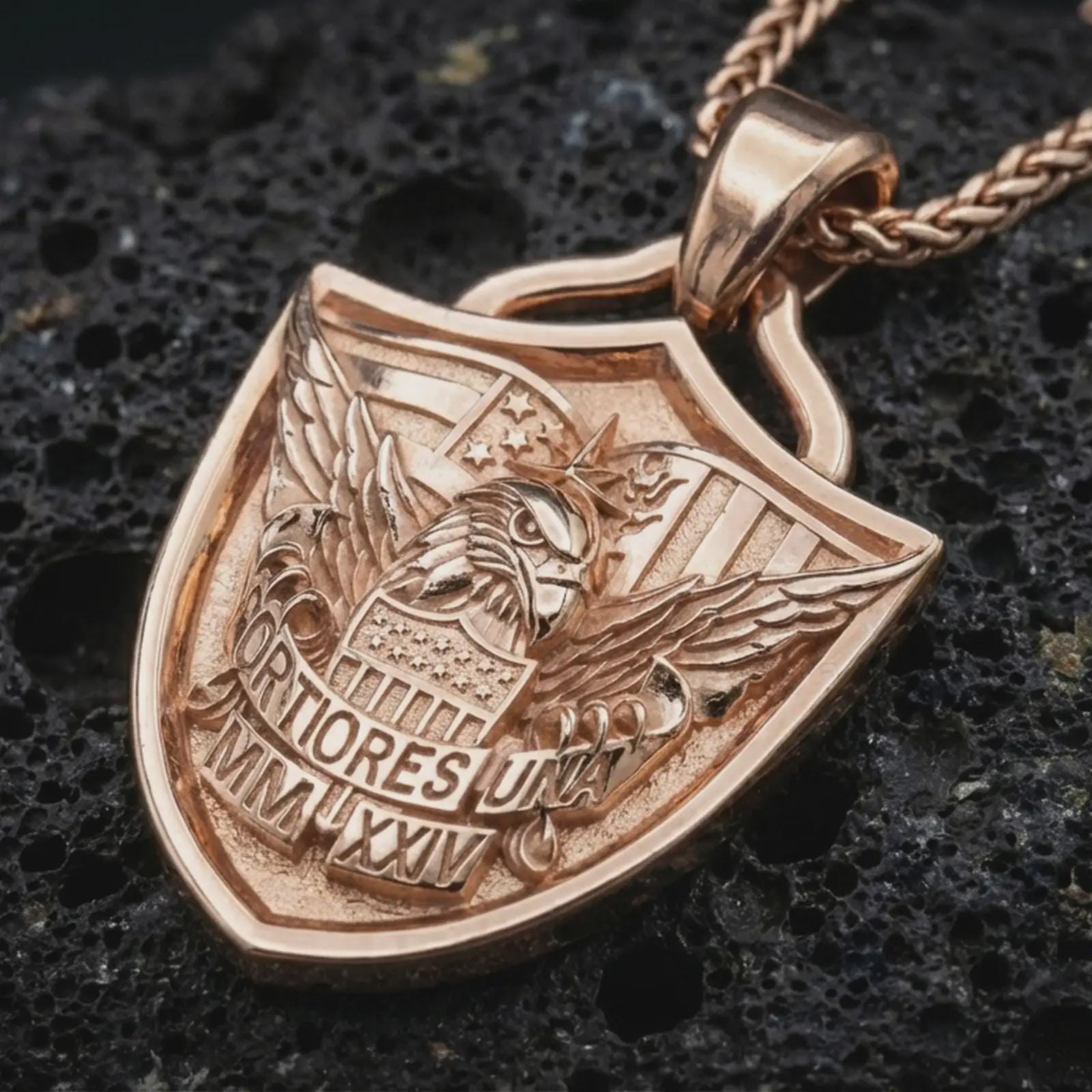 Rose gold plated Fortiores Una eagle shield pendant necklace on dark volcanic rock, photographed in a detailed premium studio macro view.