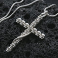 Load image into Gallery viewer, Polished silver skull cross pendant necklace displayed on black volcanic rock, shown in a refined macro product shot with stacked skull bead detail and dark gothic silhouette.
