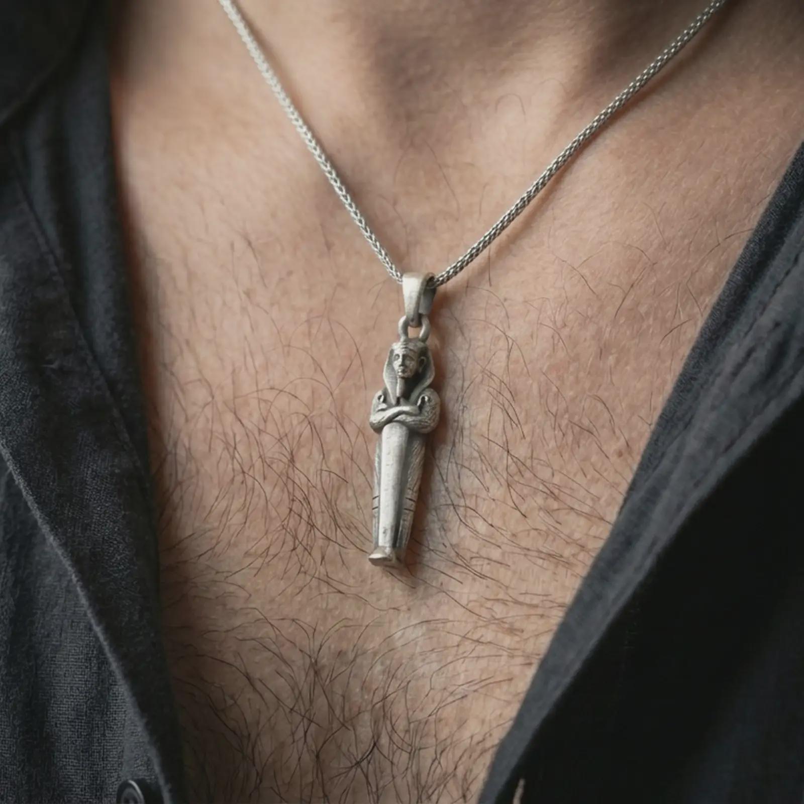 Oxidized King Tut pendant necklace worn on the neck, styled in a dark lifestyle portrait with an open shirt and masculine presentation.