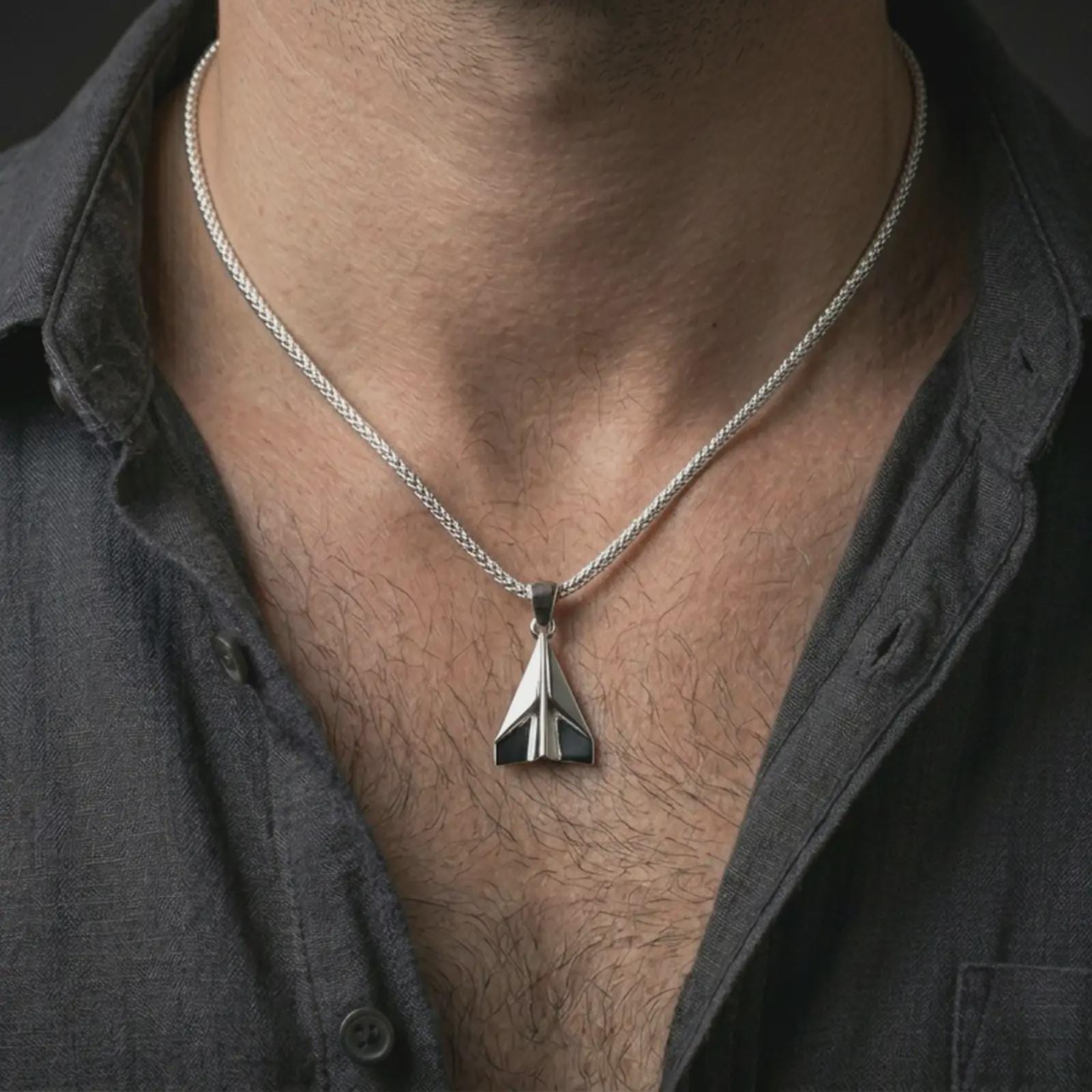 Polished silver origami airplane pendant necklace worn on the neck, shown against the chest in a clean and elegant everyday wear composition.