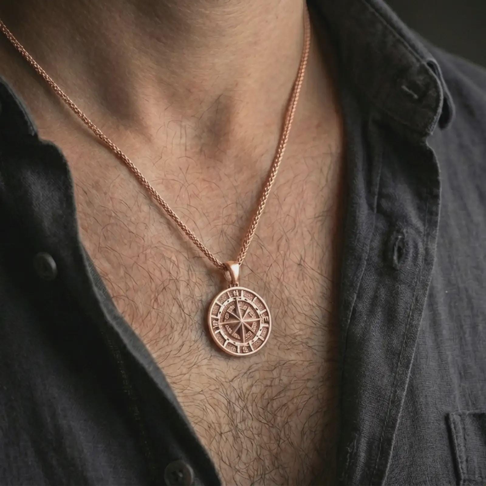 Rose gold plated compass pendant necklace worn on the neck, presented in a close-up lifestyle shot with a refined masculine aesthetic.