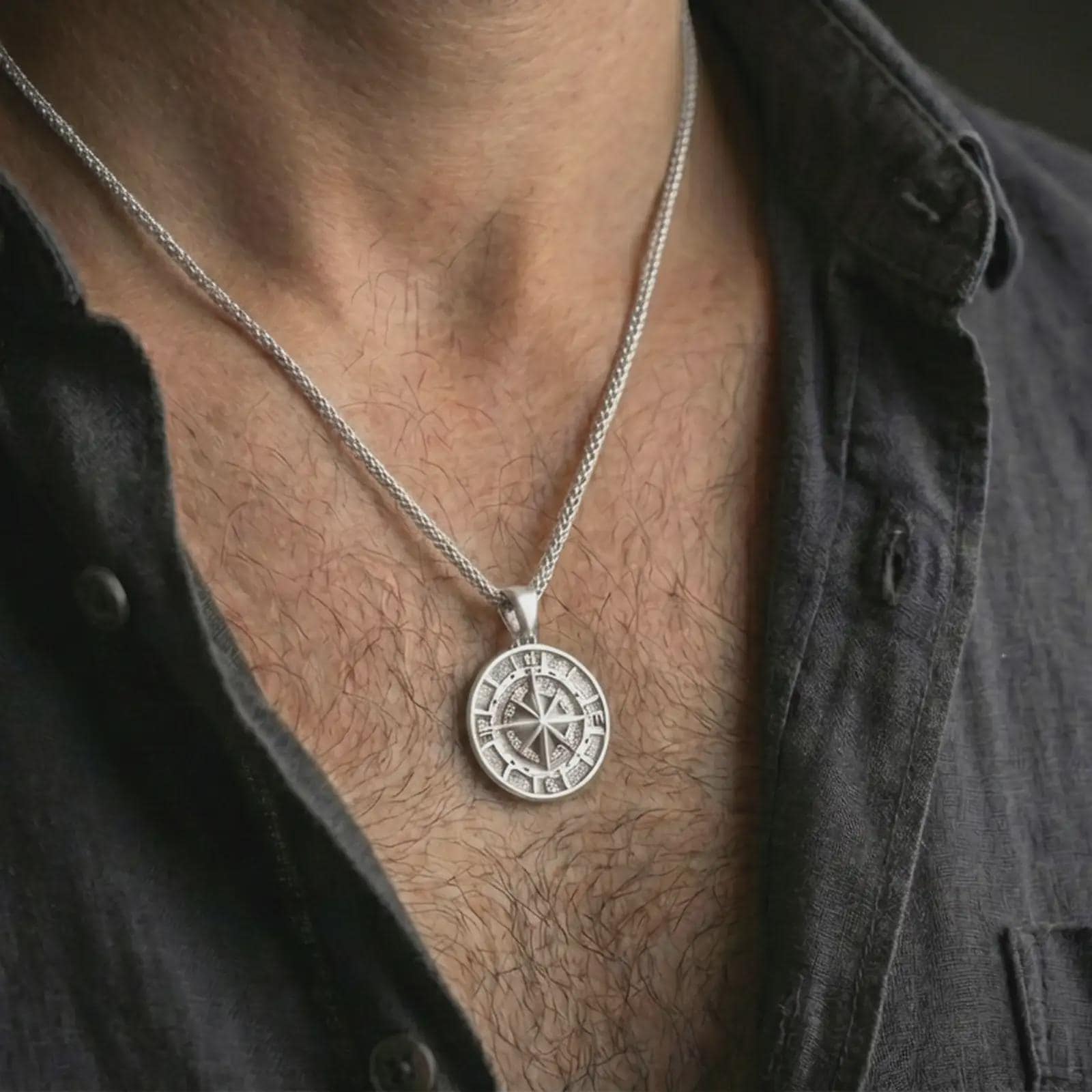 Polished silver compass pendant necklace worn on the neck, shown against the chest in a clean and elegant everyday wear composition.