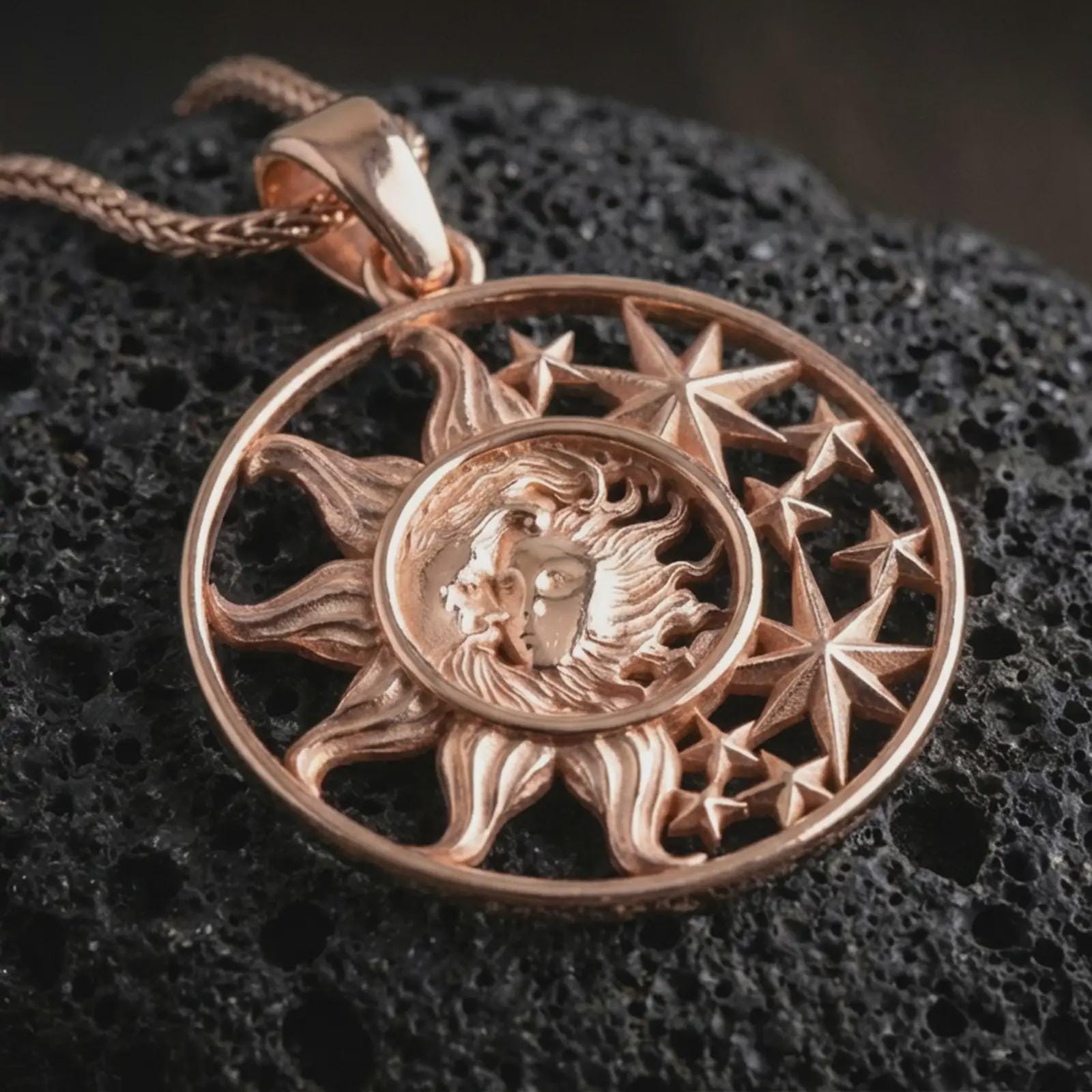 Rose gold plated sun and moon pendant necklace on dark volcanic rock, photographed in a detailed premium studio macro view.