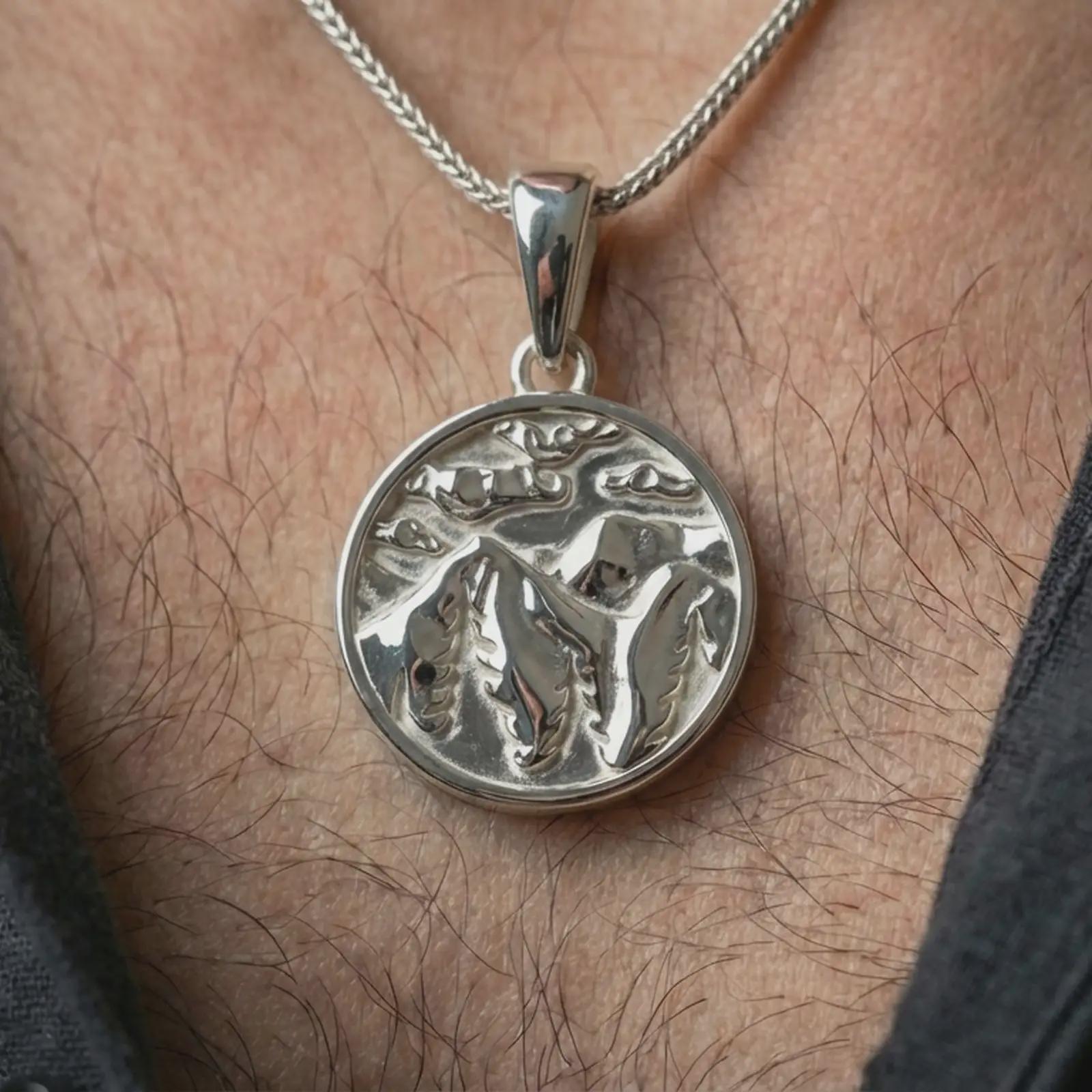 Polished silver mountain landscape pendant necklace worn on the neck, shown against the chest in a clean and elegant everyday wear composition.