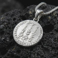 Load image into Gallery viewer, Polished silver Tiberius coin pendant necklace displayed on dark volcanic rock, shown in a premium close-up image that highlights the classical Roman portrait and historical coin medallion design.
