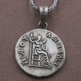 Load image into Gallery viewer, Oxidized Roman emperor coin pendant necklace resting on black volcanic stone, featuring a side profile imperial bust and antique Latin inscription in a detailed macro product photograph.
