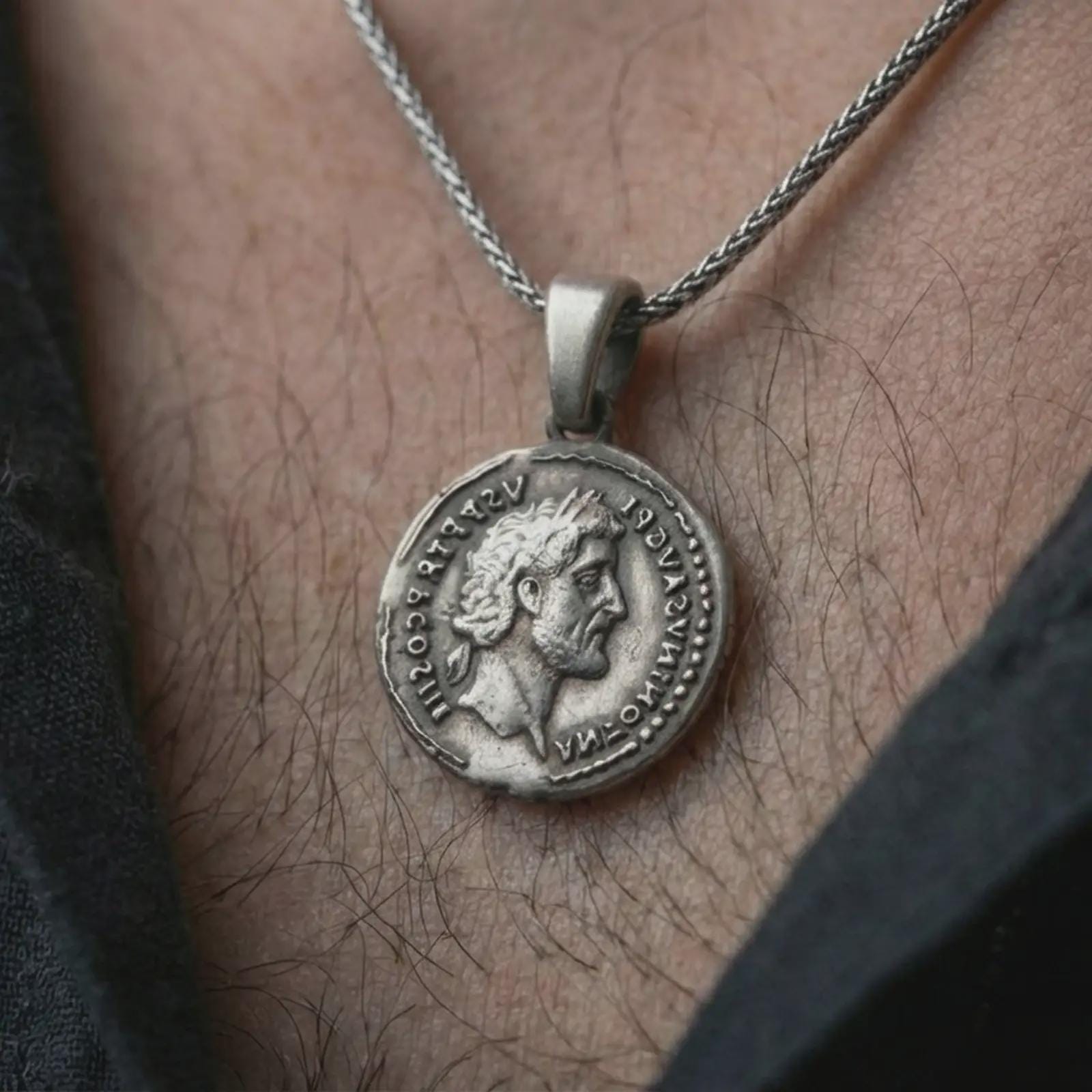 Oxidized Roman emperor coin pendant necklace worn on the neck, styled in a dark lifestyle image that presents the antique imperial coin as a bold historical statement piece.