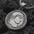 Load image into Gallery viewer, Oxidized Emperor Constans coin pendant necklace resting on black volcanic stone, featuring a Roman imperial profile with Latin inscription in a detailed antique coin-style macro photograph.
