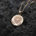 Load image into Gallery viewer, Rose gold plated heraldic eagle coin pendant necklace presented on textured volcanic stone, showcasing the crowned eagle crest and coin-inspired relief in a refined macro studio shot.
