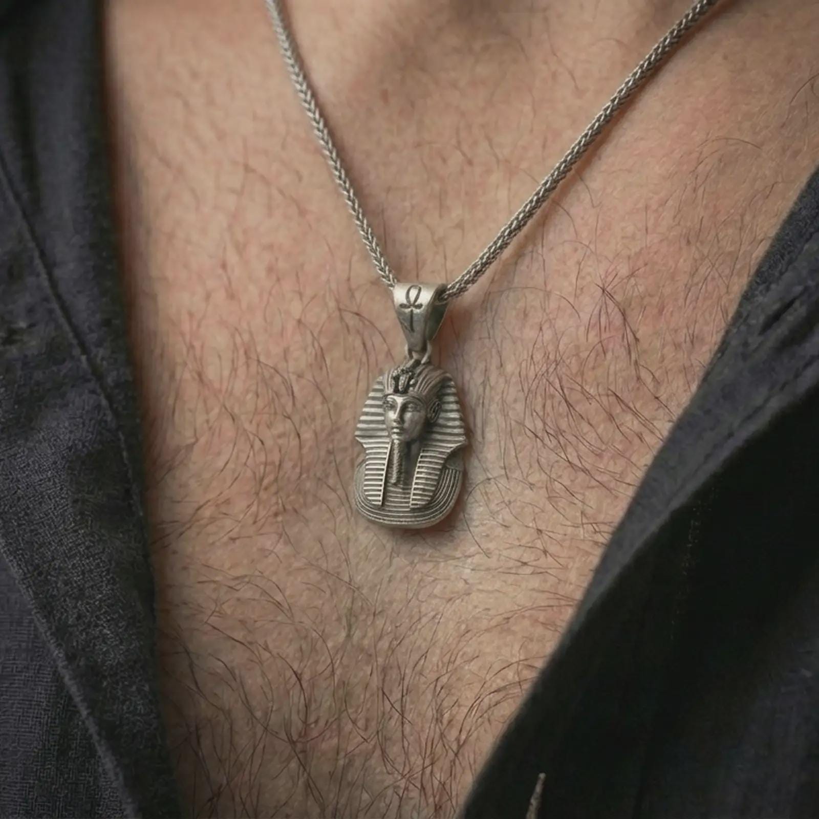 Oxidized Tutankhamun pharaoh pendant necklace worn on the neck, styled in a dark lifestyle image that presents the Egyptian king pendant as a bold historical and symbolic statement piece.