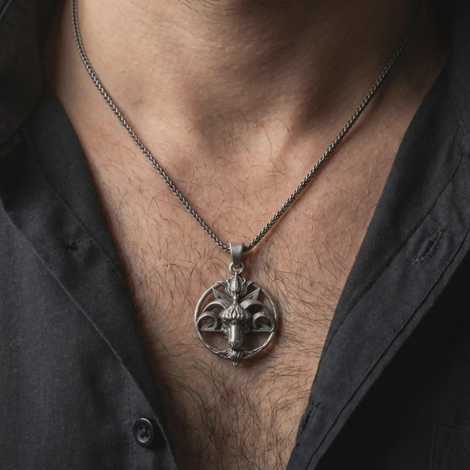 Oxidized Baphomet goat head pendant necklace worn on the neck, styled in a dark lifestyle portrait with an open shirt and masculine presentation.
