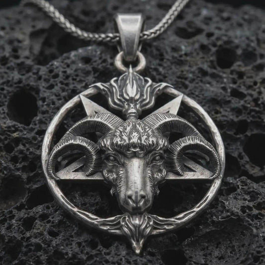 Sterling silver Baphomet goat head pendant necklace with an oxidized finish resting on textured volcanic rock, captured in a close-up premium studio composition.