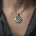 Load image into Gallery viewer, Oxidized moon and stars pendant necklace worn on the neck, styled in a dark lifestyle portrait with an open shirt and masculine presentation.
